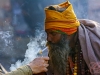 A tourist lights a cigarette for a sadhu